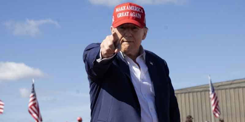 Trump wearing a MAGA hat and pointing at the camera